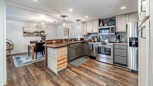 A modern kitchen with wooden flooring, stainless steel appliances, and a central island. - Mountain Cabin in Midway (Midway)