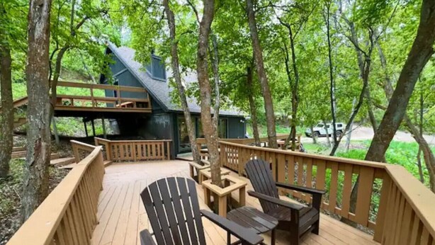 A wooden deck with outdoor furniture, including chairs and a table, surrounded by trees. - Mountain Cabin in Midway (Midway)