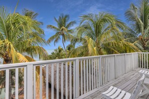 A wooden deck with a railing overlooking a beach with palm trees and the ocean. - Serenity Bay Estate-FL Keys Best Kept Secret! Beautiful, Quiet, Tropical Pardise (Marathon)