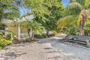 A house with a gravel driveway, surrounded by lush greenery and palm trees. - Serenity Bay Estate-FL Keys Best Kept Secret! Beautiful, Quiet, Tropical Pardise (Marathon)