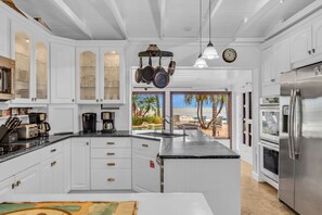 A spacious kitchen with white cabinets, a central island, and a view of the beach. - Serenity Bay Estate-FL Keys Best Kept Secret! Beautiful, Quiet, Tropical Pardise (Marathon)