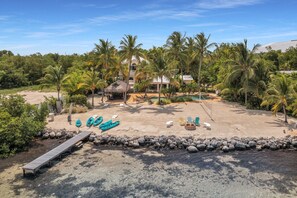 A beach resort with a pool, lounge chairs, and a thatched-roof hut. - Serenity Bay Estate-FL Keys Best Kept Secret! Beautiful, Quiet, Tropical Pardise (Marathon)