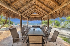 An outdoor dining area with a thatched roof, overlooking a beach and the sea. - Serenity Bay Estate-FL Keys Best Kept Secret! Beautiful, Quiet, Tropical Pardise (Marathon)
