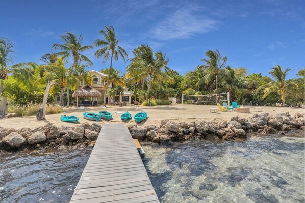 A wooden dock leading to a beach with clear water, surrounded by rocks and palm trees. - Serenity Bay Estate-FL Keys Best Kept Secret! Beautiful, Quiet, Tropical Pardise (Marathon)
