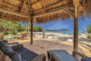 A beachside patio with wicker furniture, a thatched roof, and a view of the sea. - Serenity Bay Estate-FL Keys Best Kept Secret! Beautiful, Quiet, Tropical Pardise (Marathon)