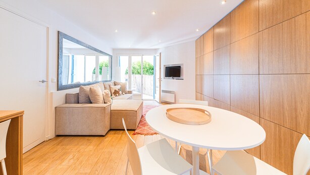 Un salon moderne avec un canapé, une table à manger ronde et un téléviseur fixé au mur.