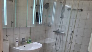 A bathroom with a toilet, sink, and glass-enclosed shower stall. - App 416 Panoramic Hotel Hohegeiß (Braunlage)