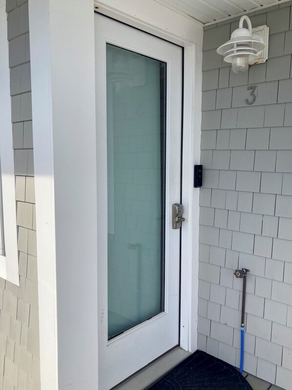 A white door with a glass panel, a metal handle, and a small mailbox on the wall.