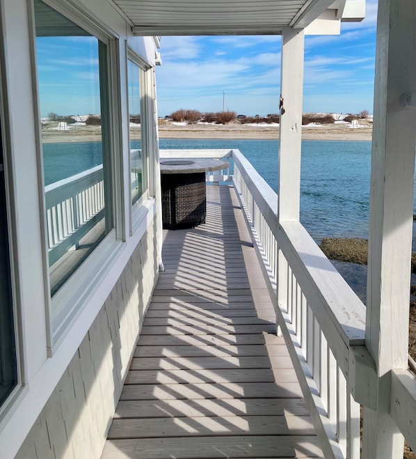 A wooden deck with a white railing overlooking a body of water.