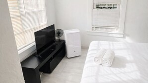 Un dormitorio moderno con cama, televisor, calentador y ventana.