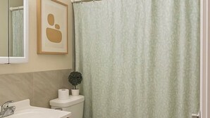Baño con inodoro, lavamanos y cortina de ducha.