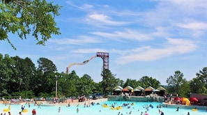 Ein Swimmingpool mit Wasserrutsche, umgeben von Bäumen und schattigen Bereichen.