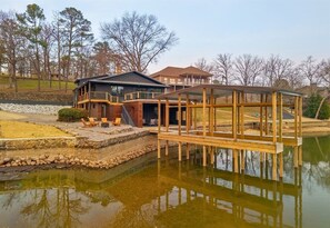 Ein Haus mit Terrasse über dem Wasser, einer Garage und einem überdachten Außenbereich.