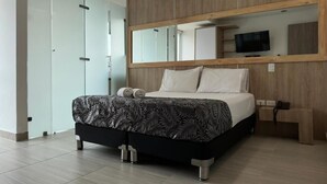 A modern hotel room with a large bed, a wooden headboard, a large mirror, and a flat-screen TV. - HOTEL PISO 12 (Bello)