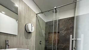 A modern bathroom with a large sink, toilet, and glass shower enclosure. - HOTEL PISO 12 (Bello)
