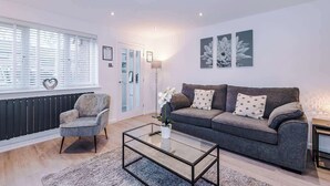 A modern living room with a grey sofa, a glass coffee table, a grey armchair, and a floor lamp. - Stylish MCR 2BR  Parking Near Etihad & Co-op (Failsworth)
