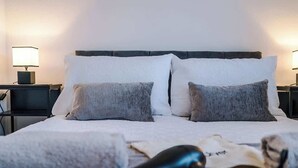 A neatly made bed with two pillows, a hairdryer, and a pair of glasses on the bed. - Stylish MCR 2BR  Parking Near Etihad & Co-op (Failsworth)