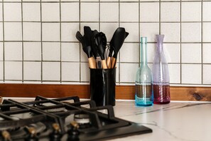 A kitchen counter with a gas stove, a utensil holder with wooden handles, and two decorative bottles. - Azalea House, in the center of Bellagio, with fitness room and private parking (bellagio)