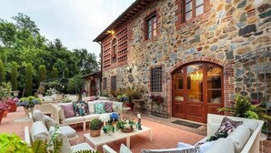 Edificio de piedra con un patio amueblado al aire libre y plantas en macetas.