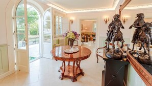 Una habitación amplia con una mesa redonda de madera, un jarrón de flores y una estatua de un jinete sobre un pedestal.