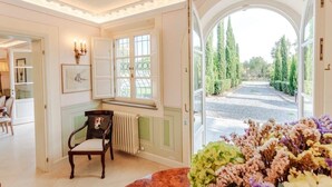 Habitación con vista a un jardín, una silla, un radiador y un cuadro en la pared.