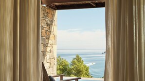 A room with a view of the ocean, a chair, and a bathtub. - Rosewood Blue Palace (Agios Nikolaos)