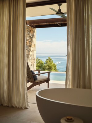A room with a view of the ocean, a chair, and a bathtub. - Rosewood Blue Palace (Agios Nikolaos)