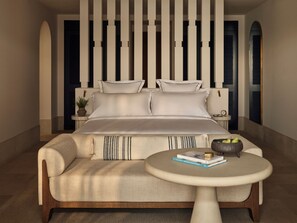 Une chambre à coucher moderne avec un grand lit, un canapé, une table ronde et un panneau décoratif mural.