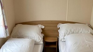 A double bed with a wooden headboard, two pillows, and a bedside table. - Sheena Beautiful Static Caravan Hoburne Devon Bay (Paignton)