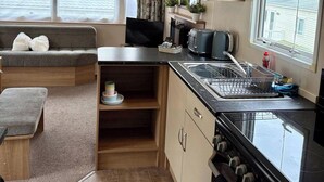 A compact kitchenette with a stove, sink, and a small countertop. - Sheena Beautiful Static Caravan Hoburne Devon Bay (Paignton)