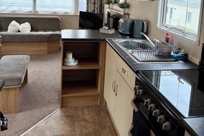 Una kitchenette compacta con estufa, lavamanos y una pequeña encimera.