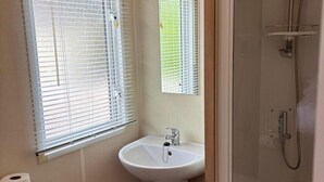 A bathroom with a white sink, a toilet, and a shower. - Sheena Beautiful Static Caravan Hoburne Devon Bay (Paignton)
