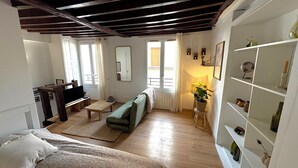A living room with a sofa, TV, and wooden flooring. - Cosy duplex in the heart of the historic center (Auxerre)