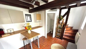 A kitchen with a wooden table, bar stools, and a vase of flowers. There is a staircase leading to another room. - Cosy duplex in the heart of the historic center (Auxerre)