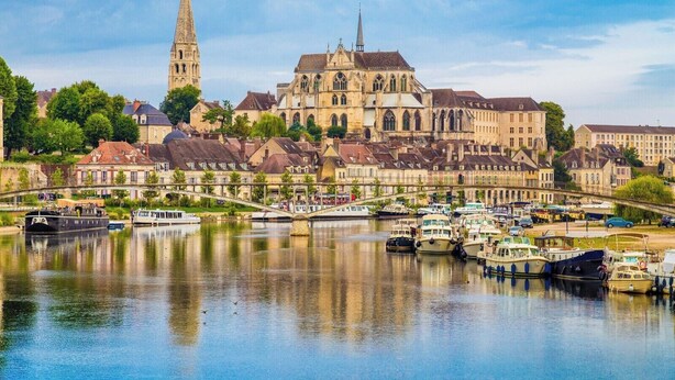 A historic cathedral with a prominent tower, surrounded by a river with boats and a bridge. - Cosy duplex in the heart of the historic center (Auxerre)