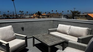 Eine Dachterrasse mit einer Couch, Stühlen und einem Tisch.