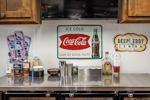 Uma área de bar com um letreiro indicando 'Gelo Que Derrete' e 'Coca-Cola', com o slogan 'Sinal de Bom Gosto'.