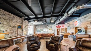 A modern lounge area with leather sofas, a pool table, and a bar area with a neon sign. - Woody’s Roadhouse Retreat: Barndominium Near Lake Alan Henry (Justiceburg)