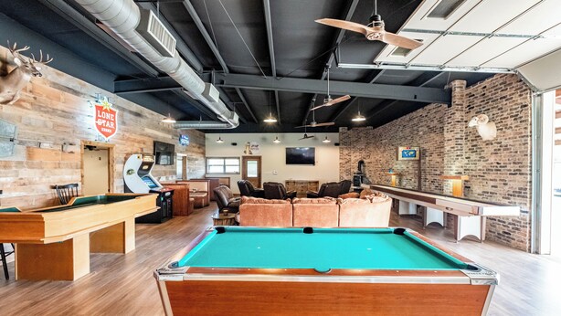 A pool table in a room with brick walls, a ceiling fan, and a Lone Star sign. - Woody’s Roadhouse Retreat: Barndominium Near Lake Alan Henry (Justiceburg)