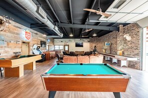 A pool table in a room with brick walls, a ceiling fan, and a Lone Star sign.
