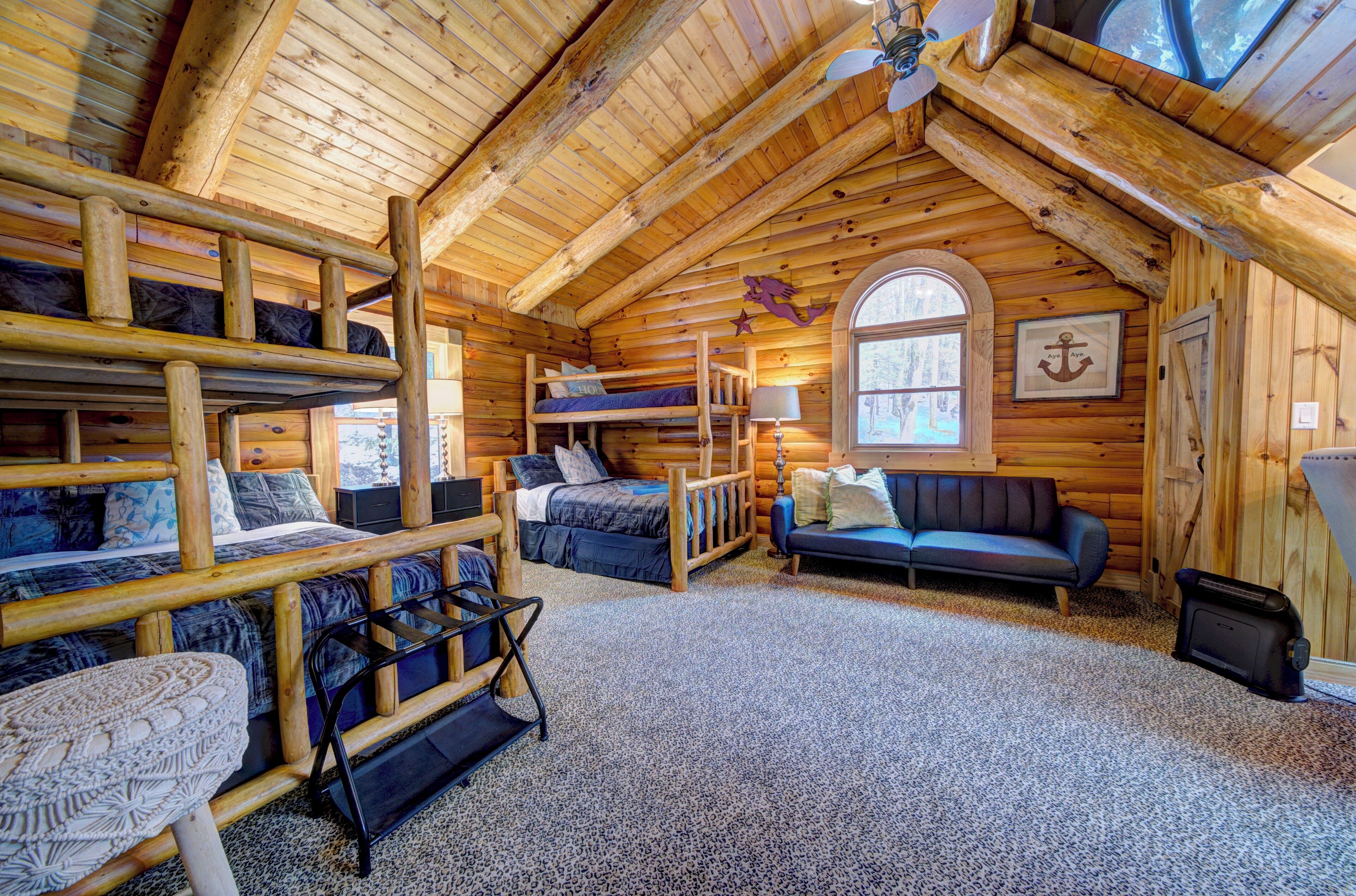 A log cabin interior with bunk beds, a sofa, and a fireplace.