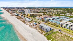 Un hotel frente al mar con varias edificaciones, una playa y una carretera.