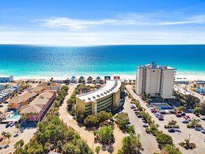 Un hotel costero con un edificio curvo, piscina y vistas al océano.