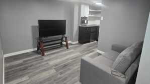 Un salón moderno con un televisor de pantalla plana, un sofá gris y una mesa de centro de madera.