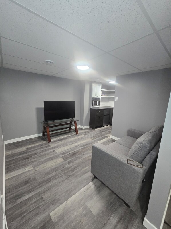 Ein modernes Wohnzimmer mit Fernseher, grauem Sofa und Couchtisch aus Holz.