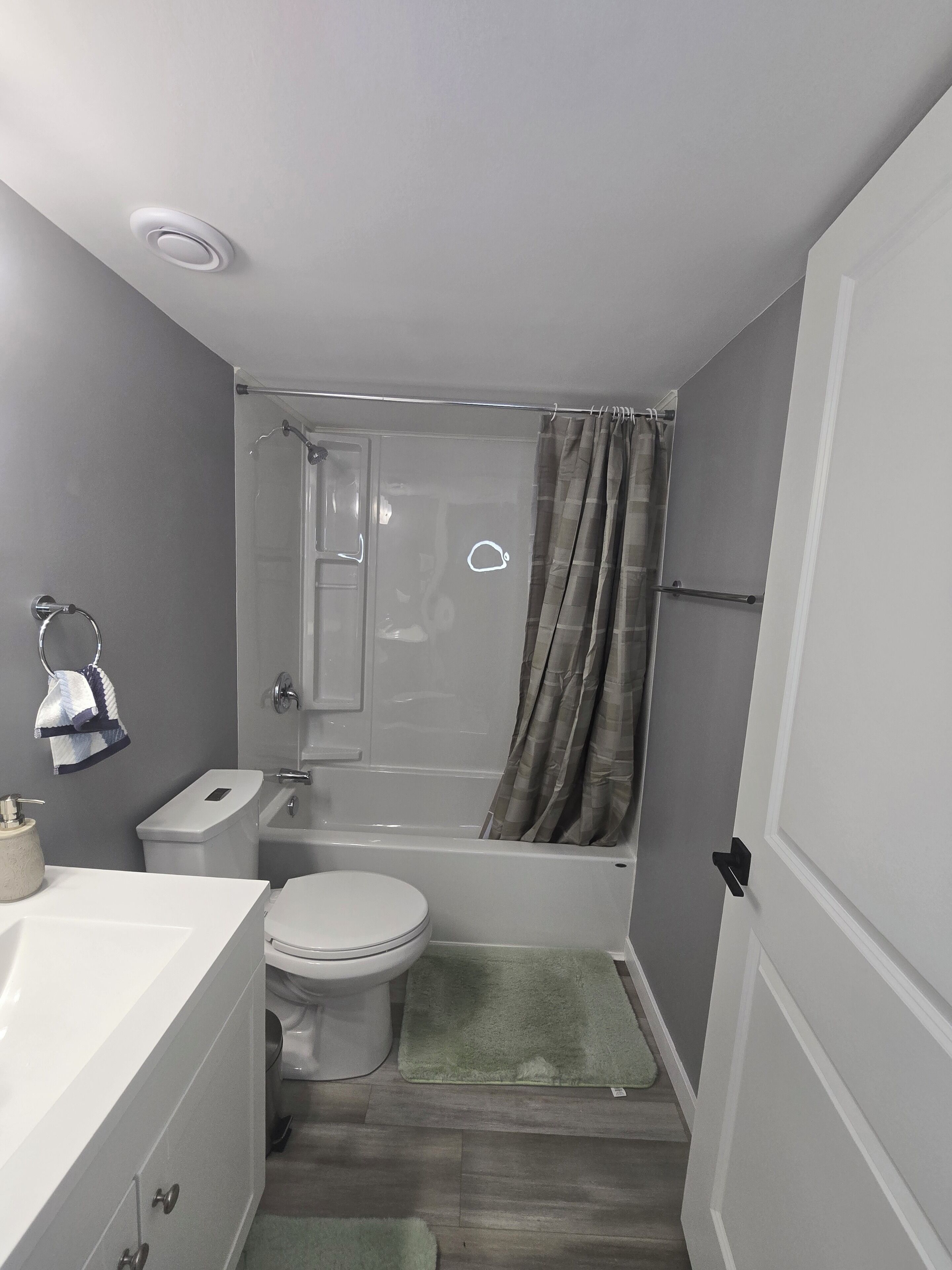 A compact bathroom with a toilet, sink, and shower.