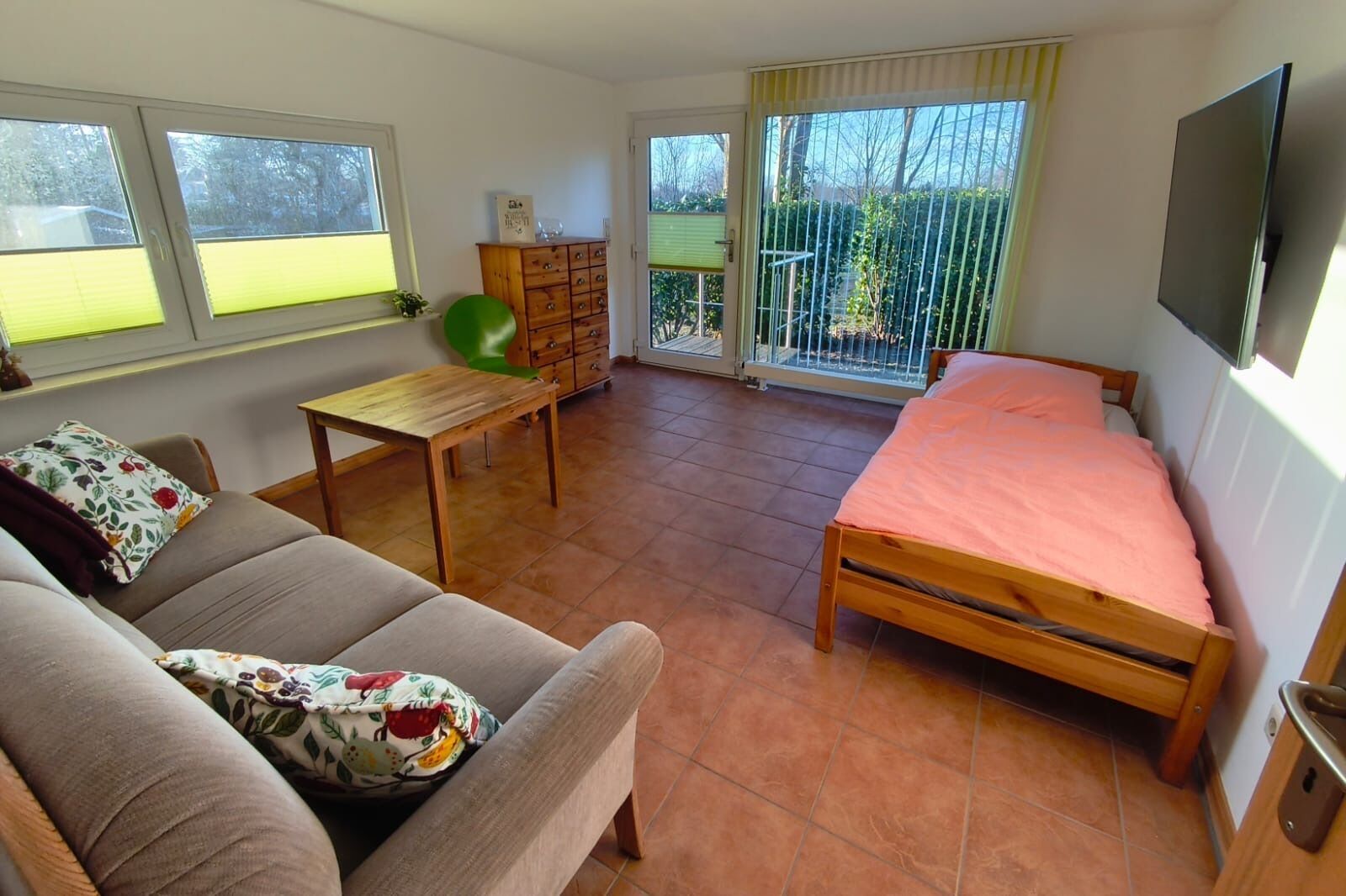 Een gezellige kamer met een bank, een houten bed, een klein tafeltje en een groene fitnessbal.