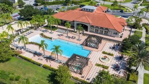 Vista aérea de un resort con una amplia piscina, zonas de descanso y un pabellón.