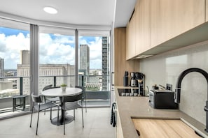 Eine moderne Küche mit einem großen Fenster, einem runden Esstisch und Blick auf die Stadtlandschaft.