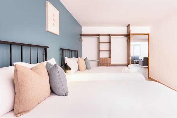 Quarto de hotel com duas camas, um guarda-roupa e uma escrivaninha.